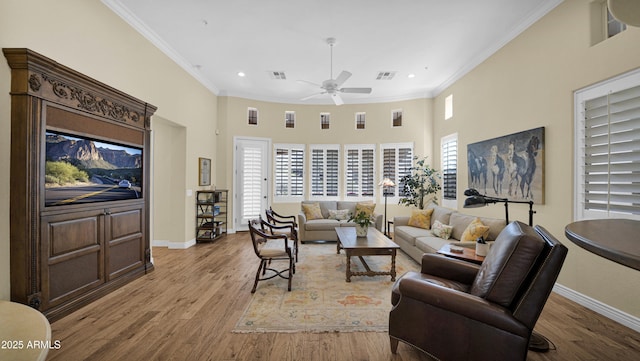 living room featuring visible vents, baseboards, wood finished floors, a high ceiling, and crown molding