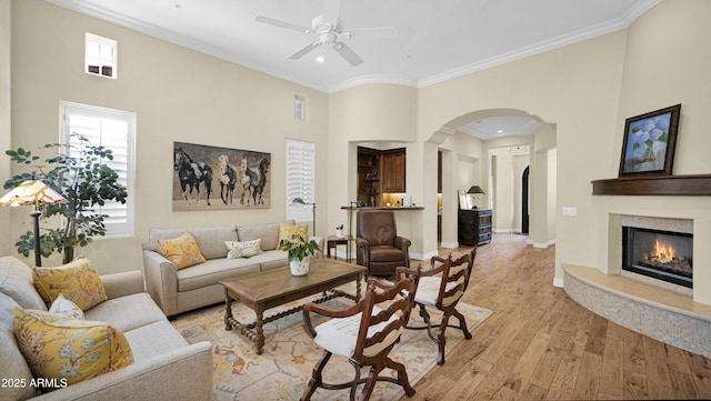 living room featuring arched walkways, light wood-style flooring, and crown molding