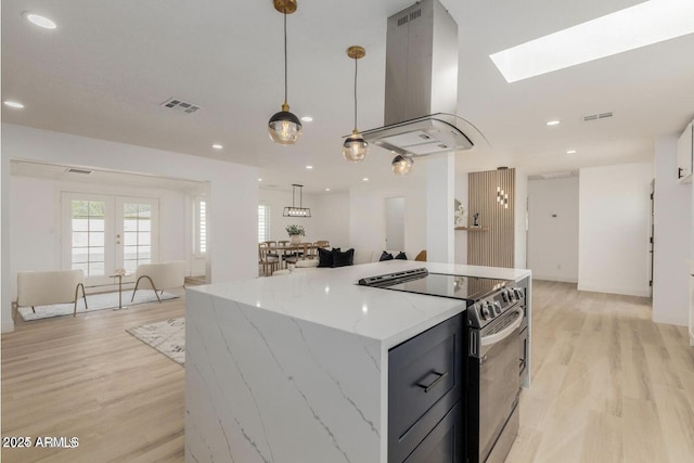 kitchen with a center island, island exhaust hood, hanging light fixtures, light stone counters, and electric range