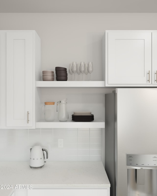 details featuring white cabinets, backsplash, stainless steel refrigerator, and light stone counters