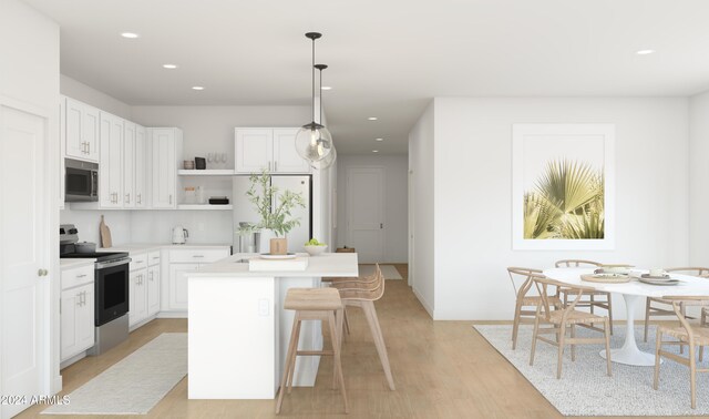 kitchen featuring white cabinets, a kitchen island, light wood-type flooring, and stainless steel appliances