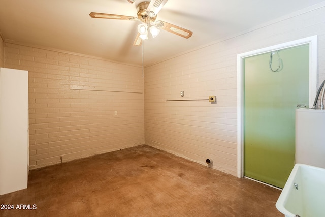 clothes washing area with ceiling fan and brick wall