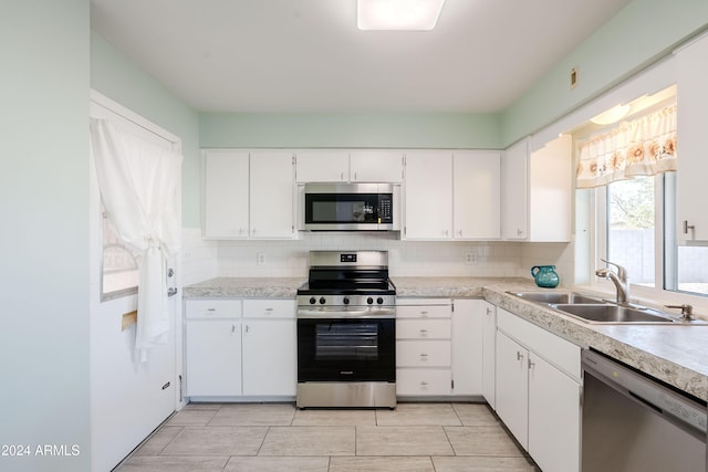 kitchen featuring decorative backsplash, sink, white cabinets, and stainless steel appliances