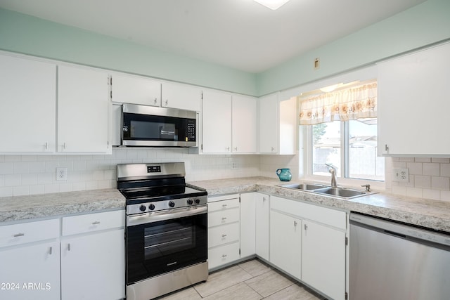 kitchen with decorative backsplash, stainless steel appliances, white cabinetry, and sink