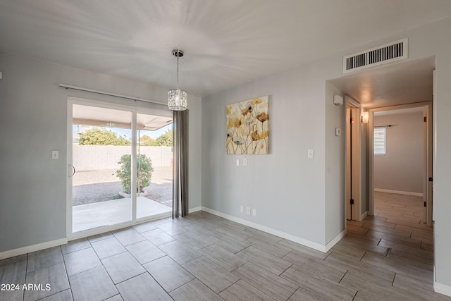 unfurnished room with an inviting chandelier