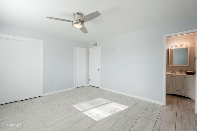 unfurnished bedroom featuring a closet, ensuite bath, ceiling fan, and sink