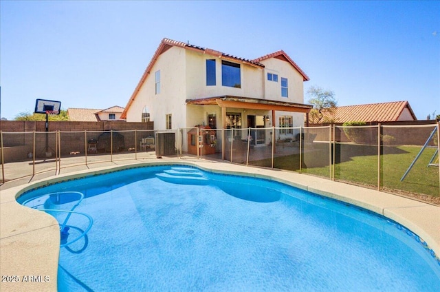 rear view of property with a fenced in pool