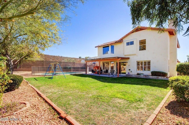 rear view of property with a patio, a lawn, a fenced in pool, and pool water feature