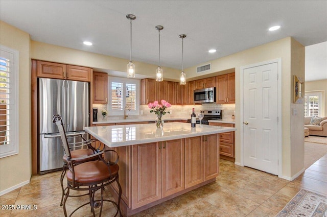 kitchen featuring sink, backsplash, a center island, stainless steel appliances, and hanging light fixtures