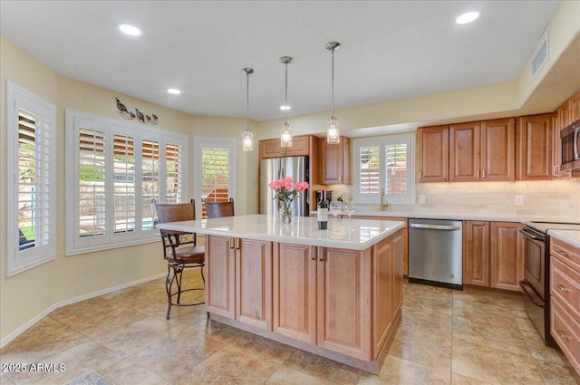 kitchen featuring a kitchen bar, backsplash, a kitchen island, decorative light fixtures, and stainless steel appliances