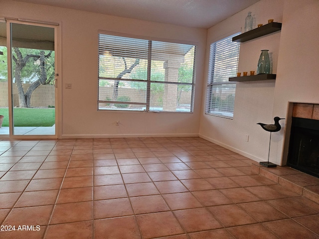 unfurnished living room featuring a tiled fireplace and light tile patterned flooring