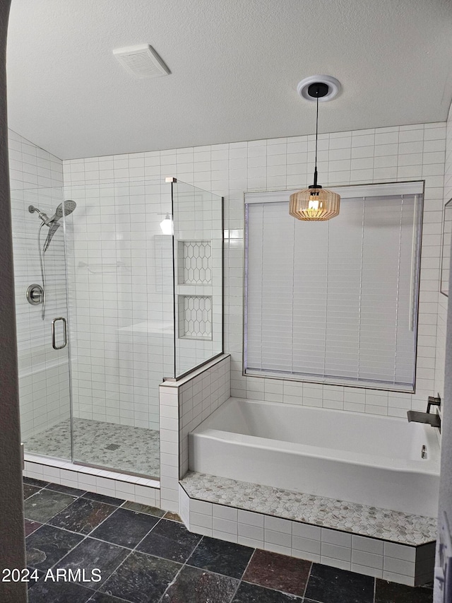 bathroom with a textured ceiling and separate shower and tub