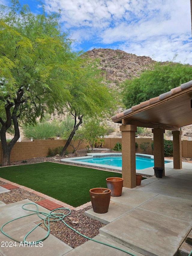 view of pool with a mountain view, a patio, and a yard