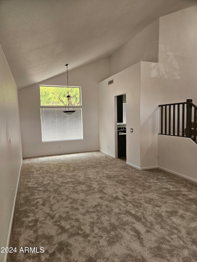 unfurnished living room featuring carpet flooring, lofted ceiling, and a textured ceiling