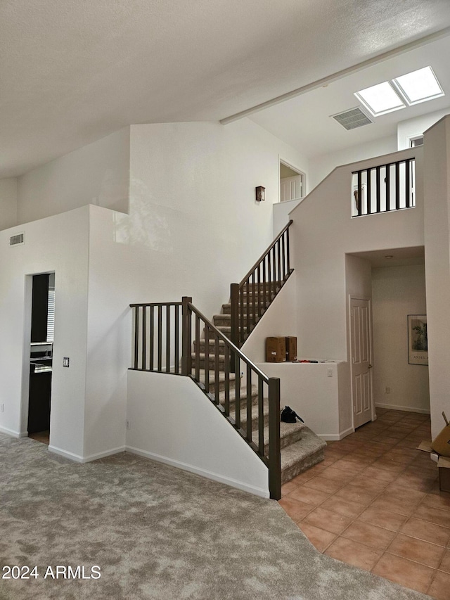 stairs featuring a textured ceiling, high vaulted ceiling, and carpet