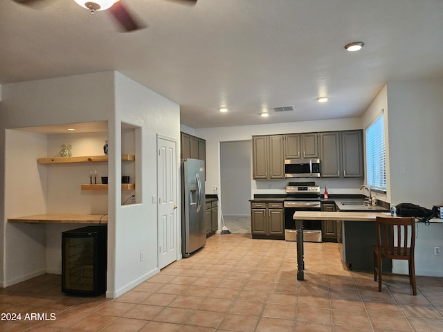 kitchen featuring stainless steel appliances, light tile patterned floors, sink, a breakfast bar area, and ceiling fan