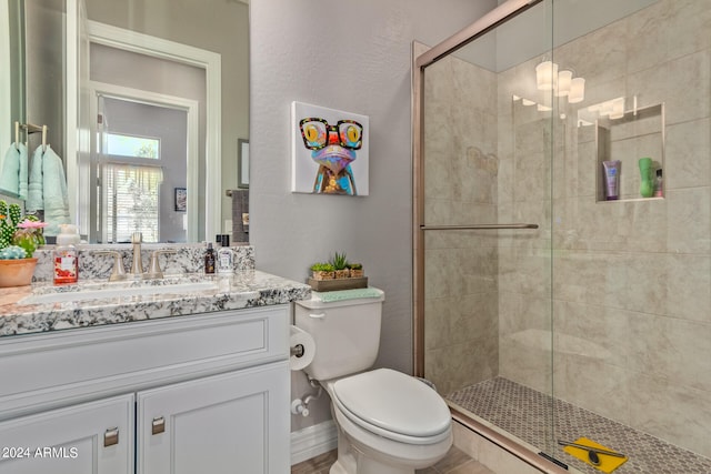 bathroom with walk in shower, toilet, and vanity with extensive cabinet space