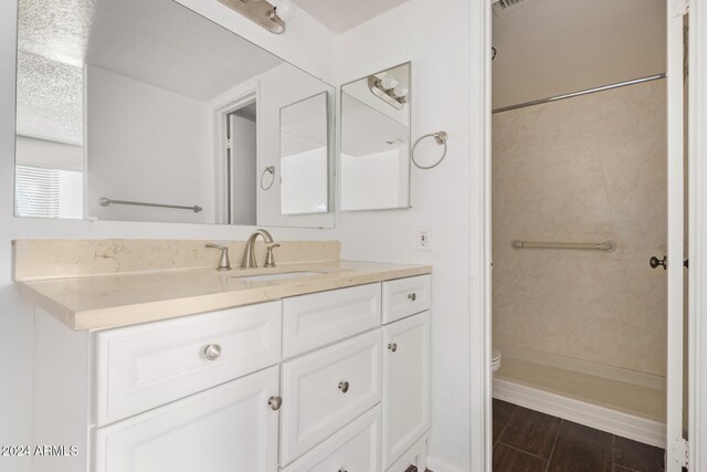 bathroom with toilet, a shower, and vanity