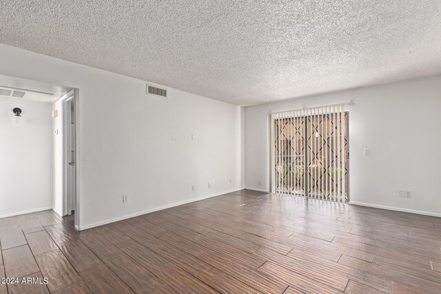 unfurnished room with dark hardwood / wood-style flooring and a textured ceiling