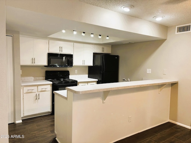 1920 W Lindner Ave Unit 137, Mesa, AZ 85202 - kitchen with black appliances, dark wood-type flooring, a peninsula, a breakfast bar, and a textured ceiling