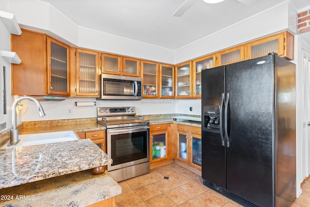 kitchen with crown molding, sink, light stone counters, appliances with stainless steel finishes, and light tile patterned floors