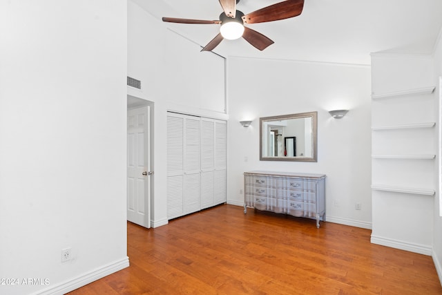 unfurnished bedroom with wood-type flooring, a closet, high vaulted ceiling, and ceiling fan