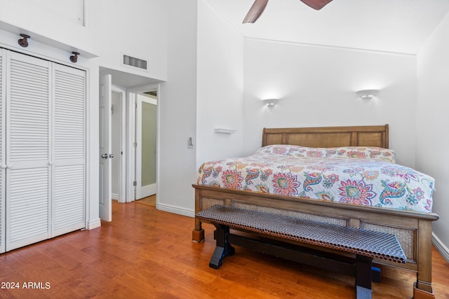 bedroom featuring a towering ceiling, ceiling fan, a closet, and hardwood / wood-style floors