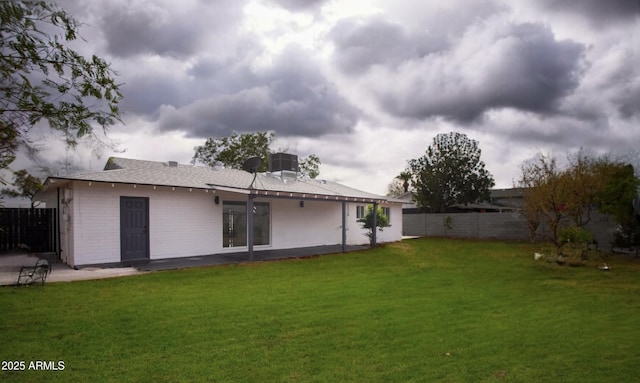 rear view of property with a lawn, a patio area, a fenced backyard, and central air condition unit