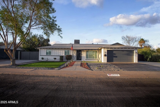 ranch-style home featuring concrete driveway, an attached garage, fence, a front lawn, and brick siding