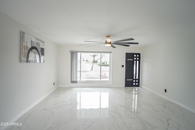 spare room with marble finish floor, baseboards, and a ceiling fan