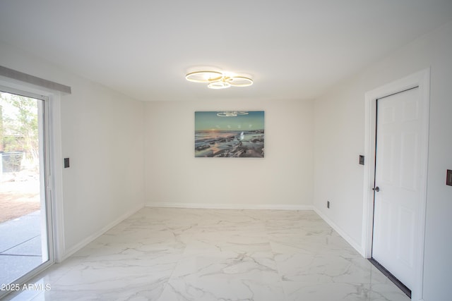 unfurnished room with marble finish floor and baseboards