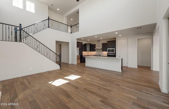 unfurnished living room featuring a high ceiling and wood-type flooring