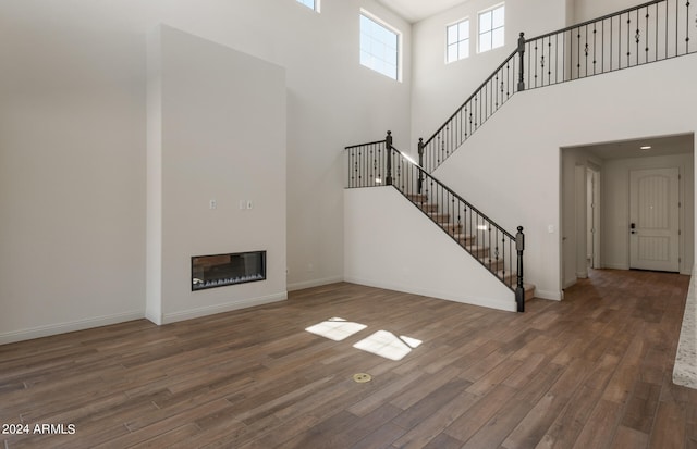 unfurnished living room with a towering ceiling and dark wood-type flooring