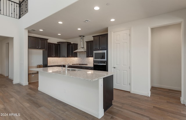 kitchen featuring appliances with stainless steel finishes, wood-type flooring, a center island with sink, and sink