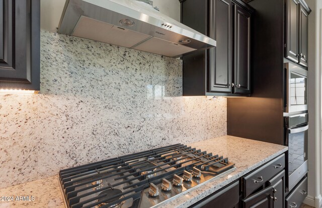 kitchen with stainless steel appliances, wall chimney range hood, and tasteful backsplash