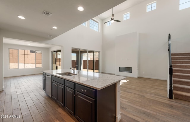 kitchen featuring dark wood-type flooring, a healthy amount of sunlight, a center island with sink, and a high ceiling