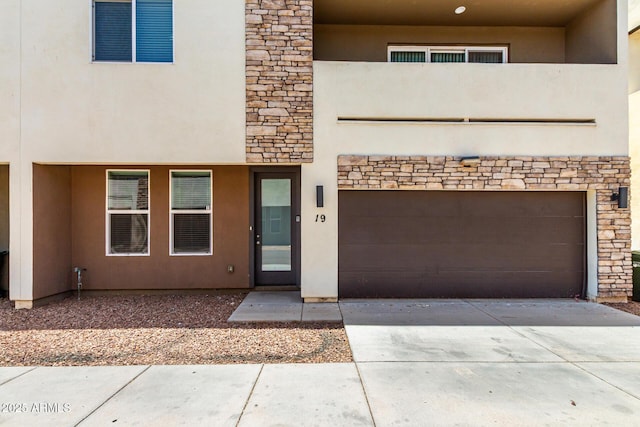 2000 N 36th St Unit 19, Phoenix, AZ 85008 - view of front of house with stone siding, a garage, stucco siding, and driveway