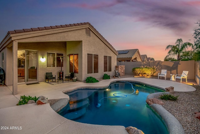 pool at dusk featuring a patio area