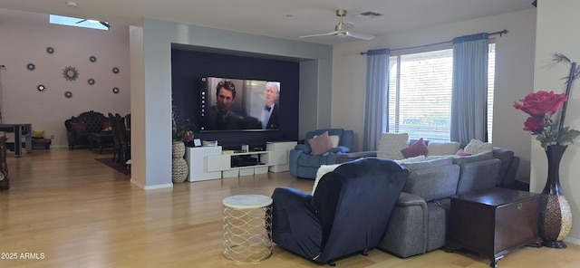 living area featuring light wood-type flooring, visible vents, a ceiling fan, and baseboards