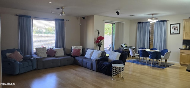 living room featuring light wood-type flooring, a ceiling fan, and visible vents