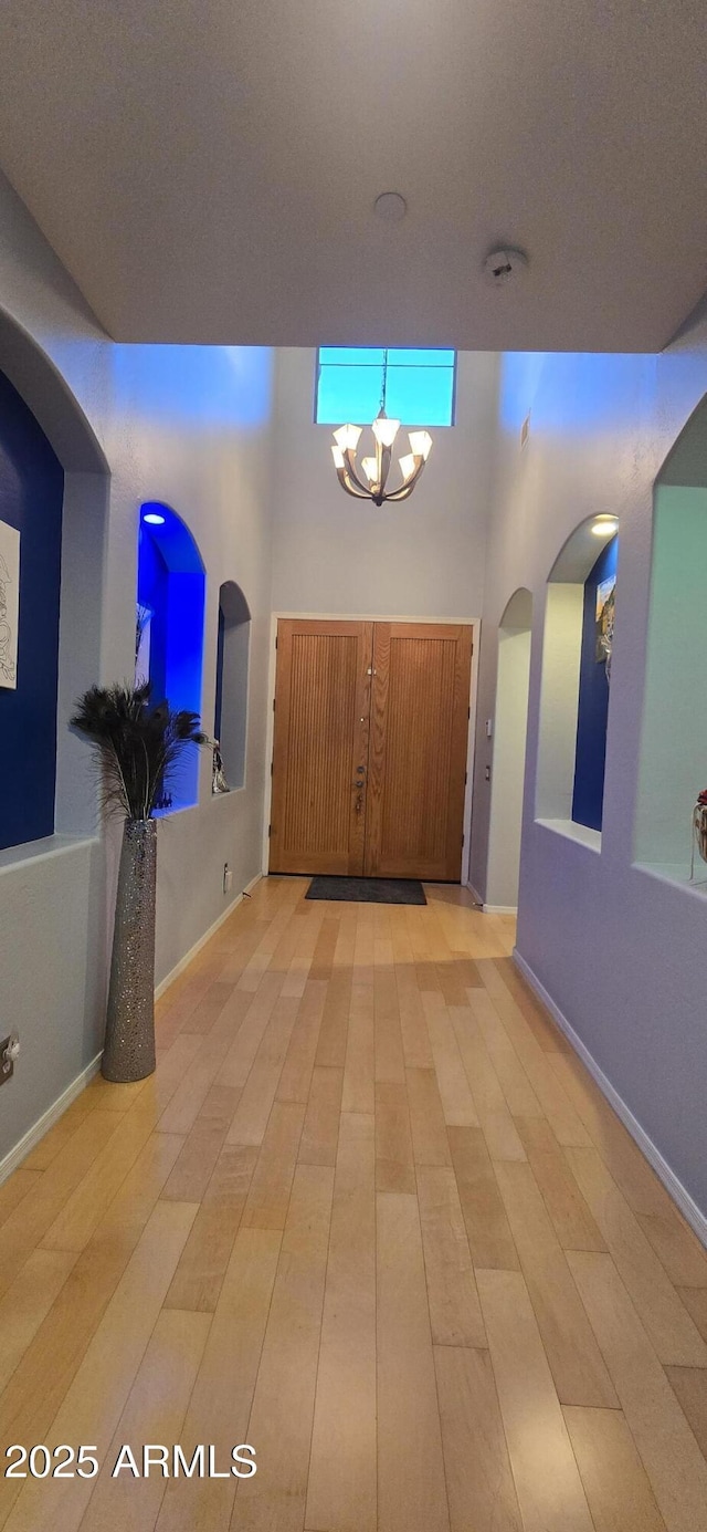 foyer entrance with light wood finished floors and a high ceiling