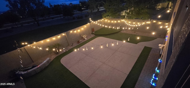 yard at night featuring a fenced backyard and a patio