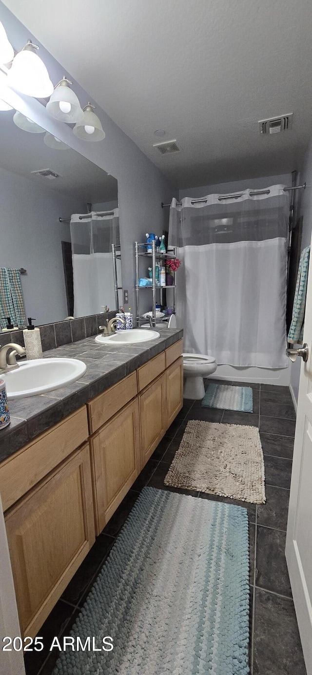 bathroom featuring tile patterned floors, a sink, and double vanity