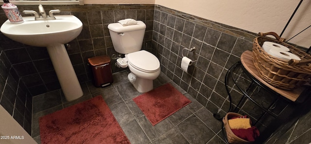 half bathroom with tile patterned flooring, tile walls, and toilet