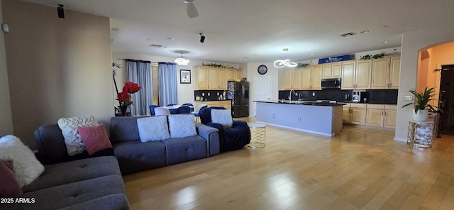 living room with arched walkways, light wood-style floors, and ceiling fan