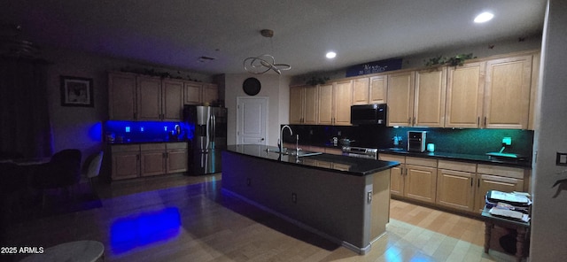 kitchen with recessed lighting, dark countertops, a sink, tasteful backsplash, and appliances with stainless steel finishes