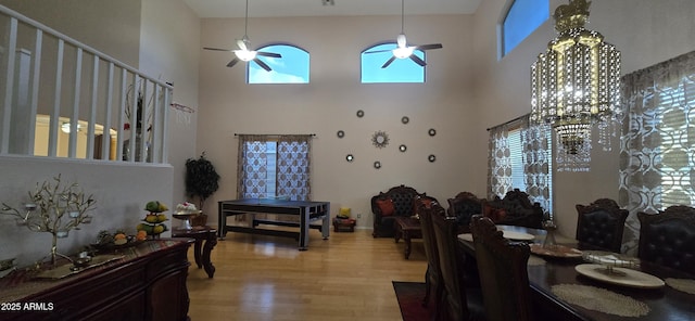 dining area with light wood-type flooring, a towering ceiling, and ceiling fan