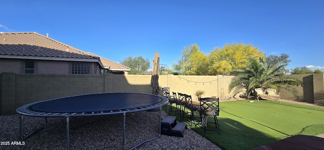 view of yard featuring a fenced backyard and a trampoline