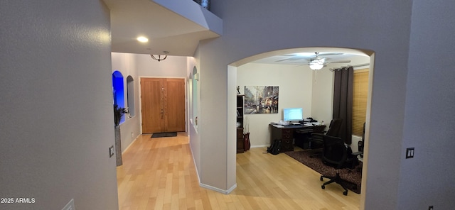 hall featuring arched walkways and light wood finished floors