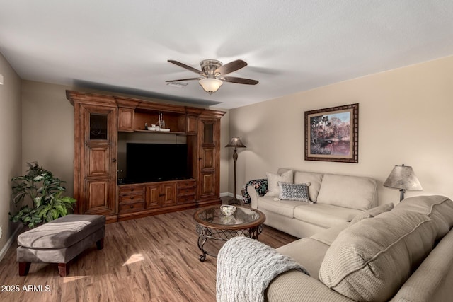 living room with light wood-style floors, ceiling fan, and baseboards